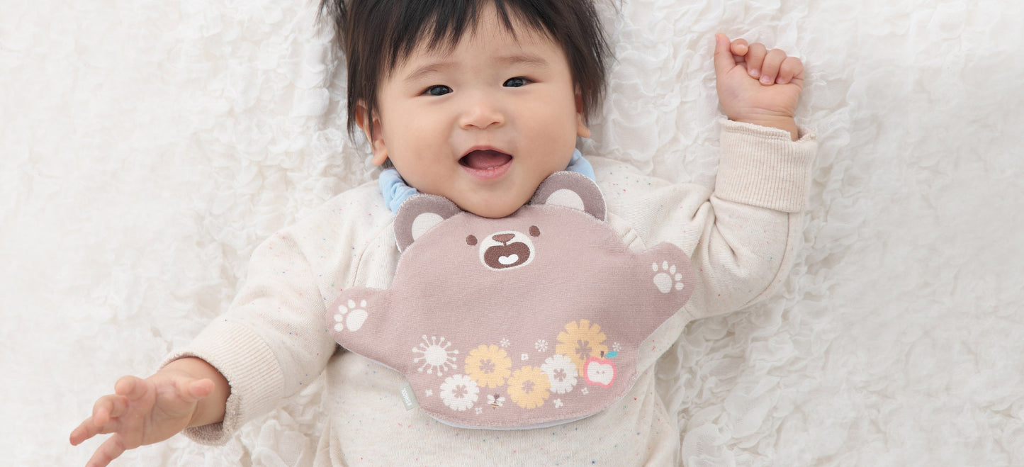 胸元にいないいないばぁスタイくまをかけた赤ちゃん
