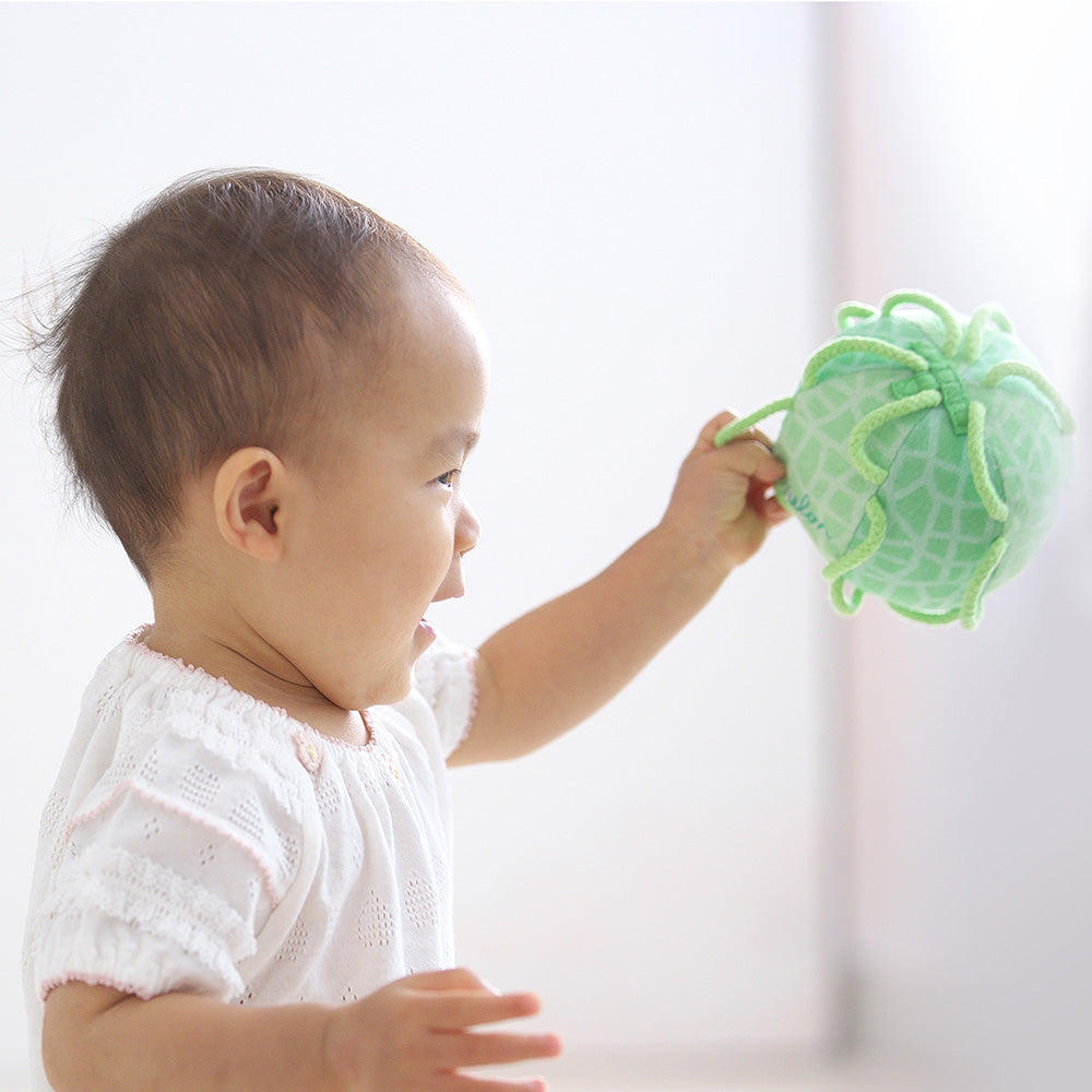 左手にわっかボールめろんを持つ赤ちゃん