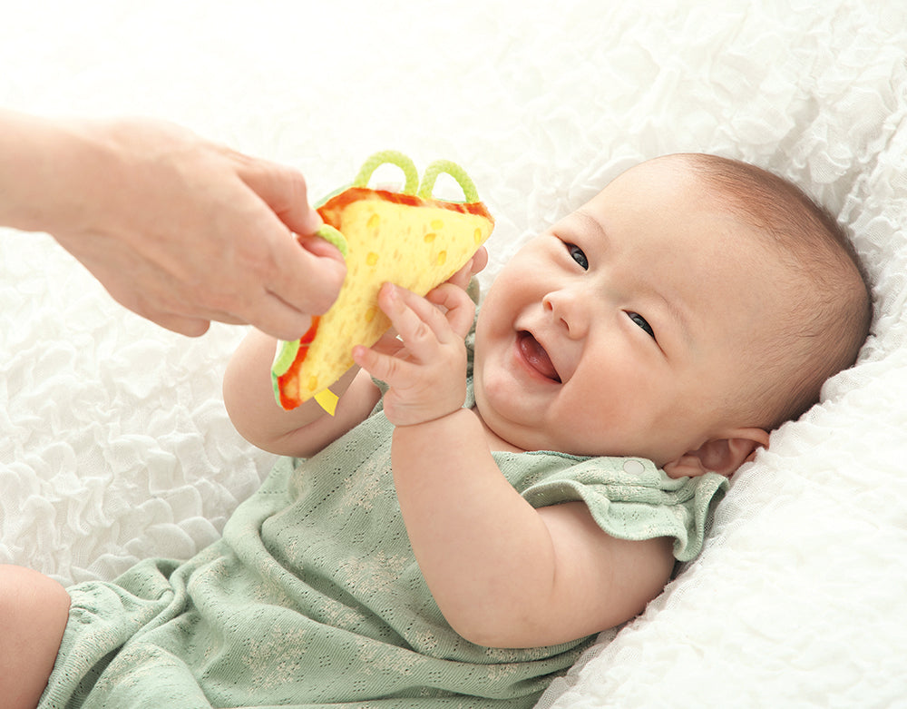 わっかラトルサンドイッチで遊ぶ笑顔の赤ちゃん